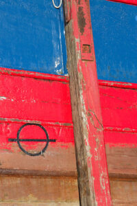 Photo, photographie de détail de coque de bateau du Finistère, bleu, rouge, marron, blanc, noir, avec une béquille @ Christophe Pluchon