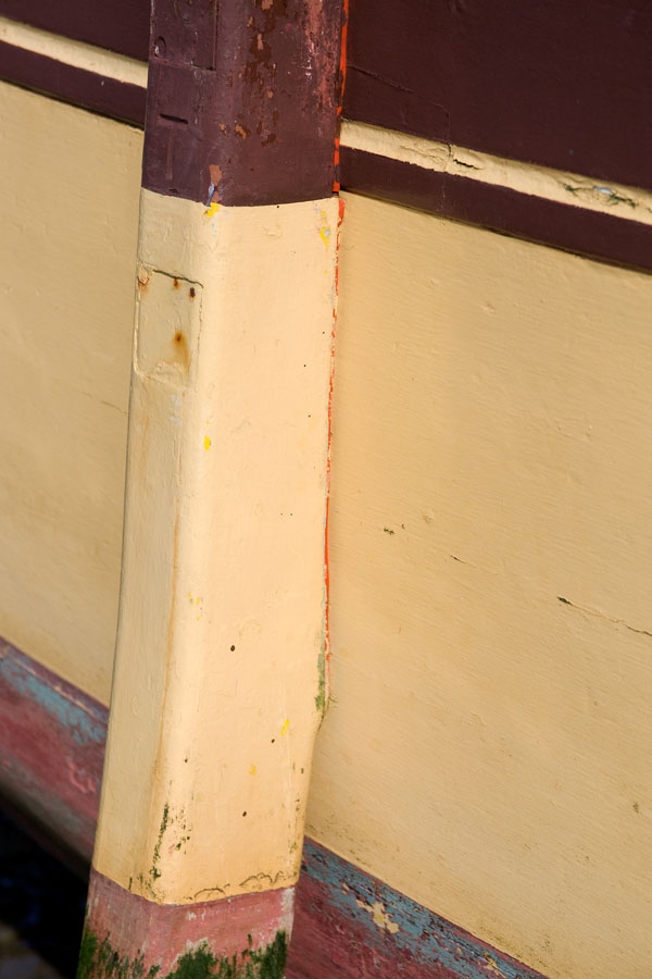 Photo, photographie de détail de coque de bateau du Finistère, jaune, beige, rouge, bordeaux, bleu, vert, avec une béquille @ Christophe Pluchon