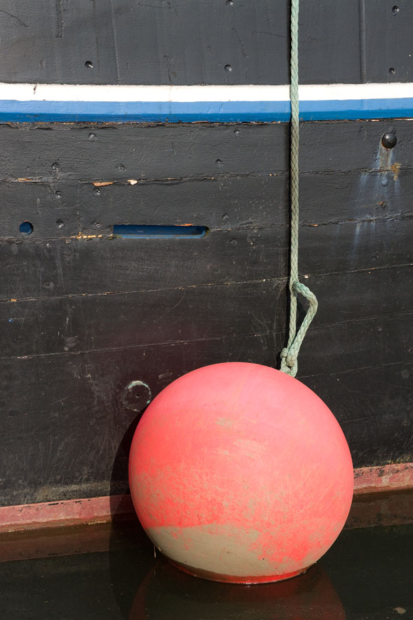 Photo, photographie de détail de coque de bateau du Finistère, bleu, blanc, noir et rouge avec bouée rouge au bout d'une corde ou d'un cordage vert @ Christophe Pluchon