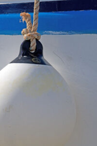 Photo, photographie de détail de coque de bateau du Finistère, bleu et blanc. Grosse bouée au bout d'une corde ou d'un cordage @ Christophe Pluchon