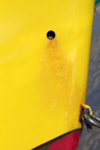 Photo, photographie de détail de coque de bateau du Finistère, jaune et rouge, avec du sable marron en arrière-plan @ Christophe Pluchon