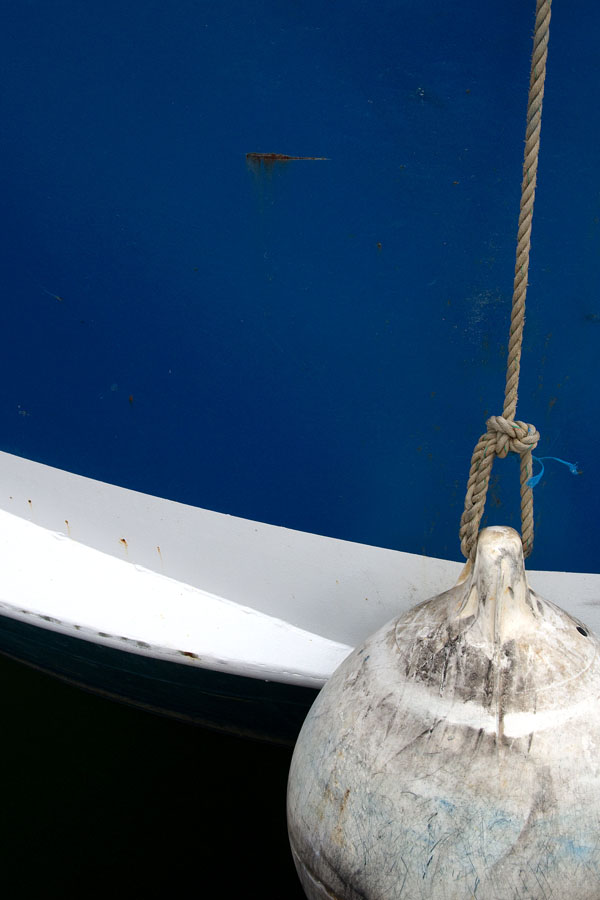 Photo, photographie de détail de coque de bateau du Finistère, bleu, noir et blanc avec une bouée couleur blanc et une corde ou cordage gris @ Christophe Pluchon