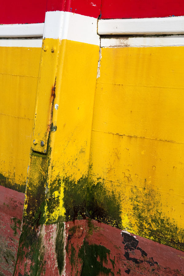 Photo, photographie de détail de coque de bateau du Finistère, rouge, blanc, jaune, vert avec une béquille salie par les algues @ Christophe Pluchon
