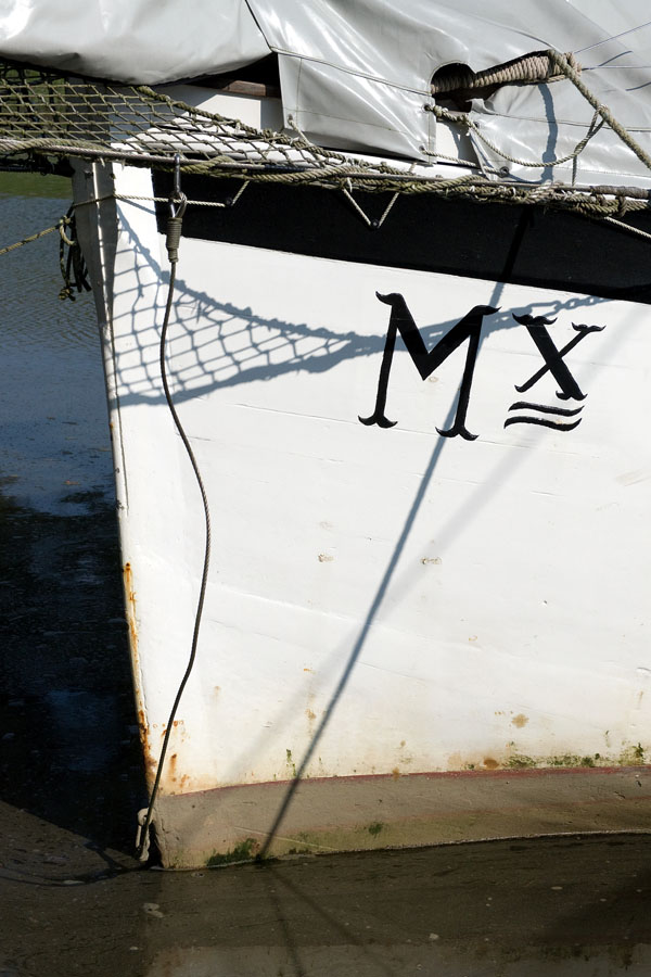 Photo, photographie de détail de coque de bateau du Finistère. Proue d'un voilier blanc et noir immatriculé dans le quartier maritime de Morlaix avec un filet et une bâche @ Christophe Pluchon