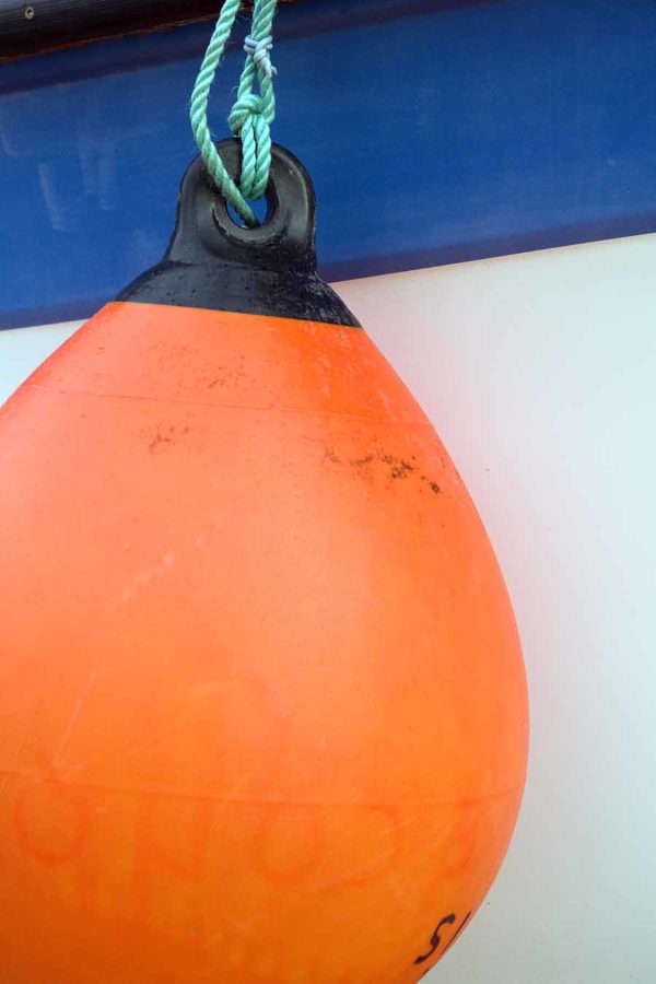 Photo, photographie de détail de coque de bateau du Finistère, bleu, vert, blanc, orange, noir, avec une grosse bouée et une corde ou un cordage @ Christophe Pluchon