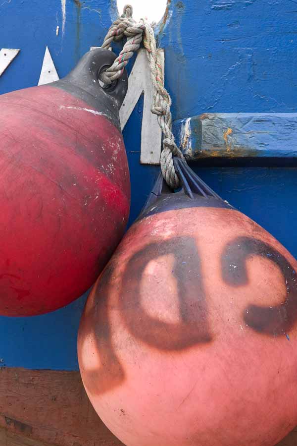 Photo, photographie de détail de coque de bateau du Finistère, bleu, rouge, orange, marron, avec une bouée et une corde ou un cordage @ Christophe Pluchon