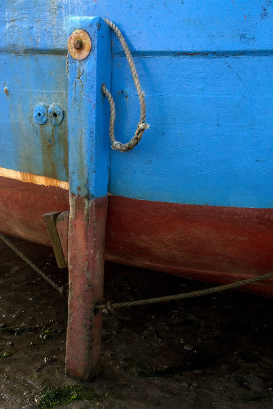 Photo, photographie de détail de coque de bateau du Finistère, bleu, rouge, marron, noir, rouille, orange, avec une béquille et une corde ou un cordage @ Christophe Pluchon