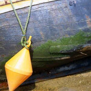 Photo, photographie de détail de coque de bateau du Finistère, jaune, bleu, vert, marron, blanc, avec une bouée sur le sable retenue par une corde ou un cordage @ Christophe Pluchon
