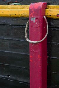 Photo, photographie de détail de coque de bateau du Finistère, rouge, noir, jaune, vert, avec une béquille, une corde ou un cordage @ Christophe Pluchon