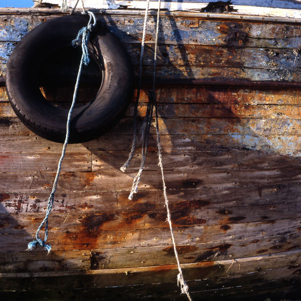 Photo, photographie de détail de coque de bateau du Finistère, marron, orange, bleu, noir, blanc, avec un pneu et une corde ou un cordage @ Christophe Pluchon