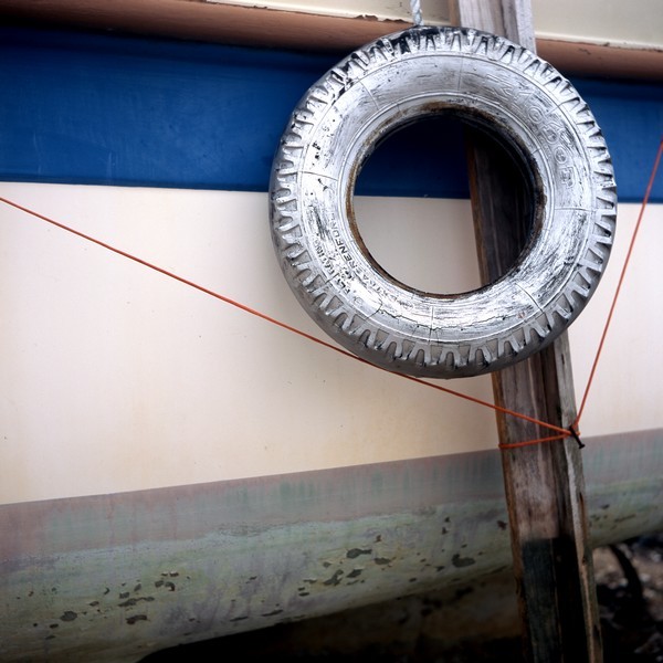 Photo, photographie de détail de coque de bateau du Finistère, bleu, blanc, gris, vert, rouge, marron, avec un pneu, une béquille et une corde ou un cordage @ Christophe Pluchon