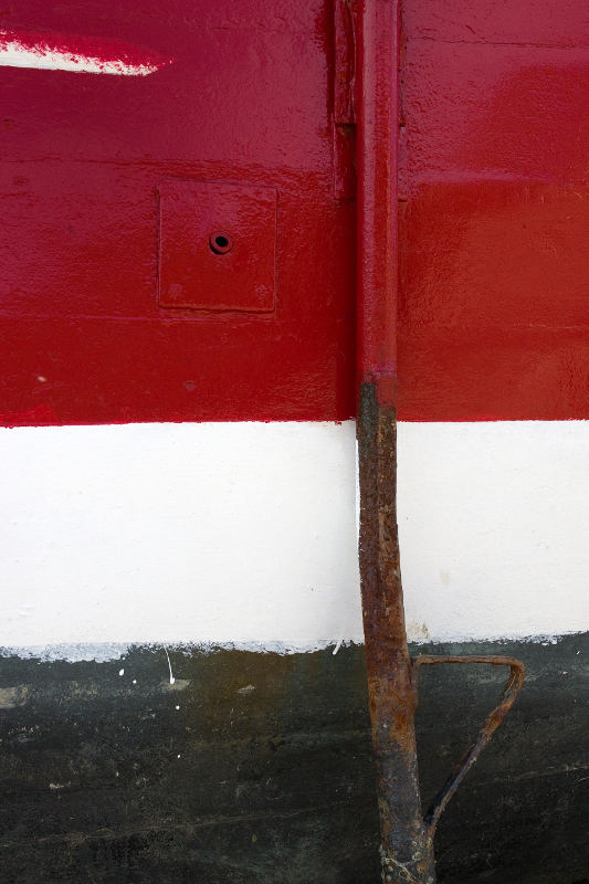 Photo, photographie de détail de coque de bateau du Finistère, rouge, noir, marron et blanc, avec une béquille et de la rouille @ Christophe Pluchon