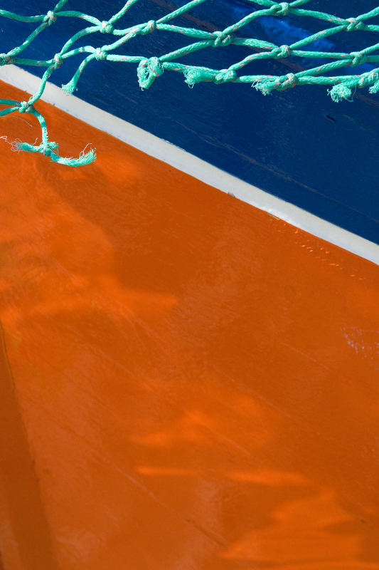 Photo, photographie de détail de coque de bateau du Finistère, orange, bleu, vert et blanc, avec un filet @ Christophe Pluchon